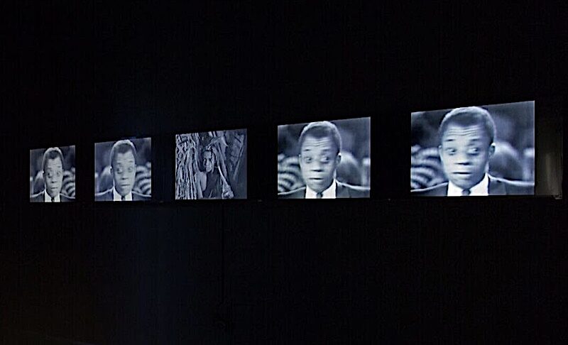 A series of five monitors all showing an image of writer James Baldwin