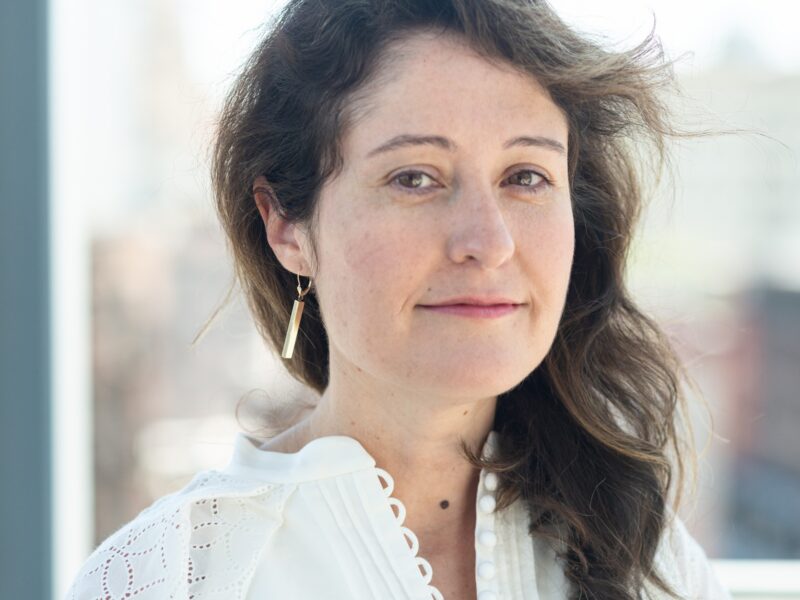 Image a woman with brown hair wearing a while blouse.